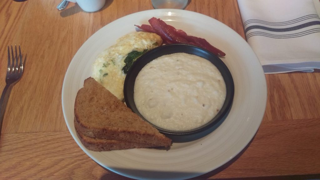 Divine breakfast platter with creamy grits, vegetable omelet and turkey bacon. 